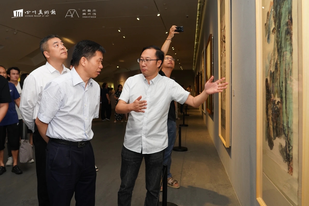 四川省文联党组副书记王忠臣（右二）、四川美术馆馆长吴晓东（右一）观看晏济元作品（图片由四川美术馆提供）